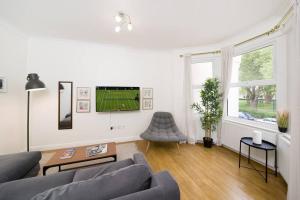 a living room with a couch and a tv at Delphina - Spacious 2BR Modern Maisonette in London