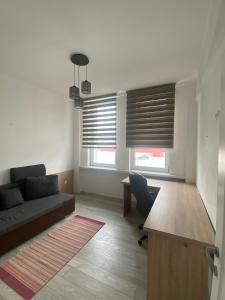 un soggiorno con divano e scrivania e 2 finestre di Apartament Claudia a Baia Mare
