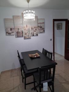 una mesa de comedor negra con sillas y una lámpara de araña en sweet house close to airport en El Prat de Llobregat