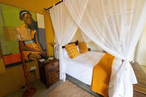 sypialnia z łóżkiem z baldachimem i białymi zasłonami w obiekcie Oriole Bush Cottage w mieście Hoedspruit