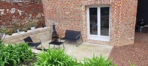 a patio with chairs and a guitar next to a brick building at La Grange in Woignarue