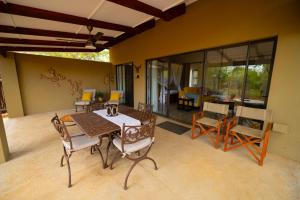 a patio with a table and chairs and a living room at Oriole Bush Cottage in Hoedspruit