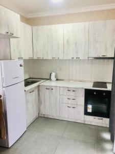 a kitchen with white cabinets and a white refrigerator at T&M Cottages in Bakuriani