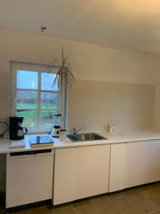 a white kitchen with a sink and a window at Countryside home 300m to the Fishing river Lille Ø in Langå