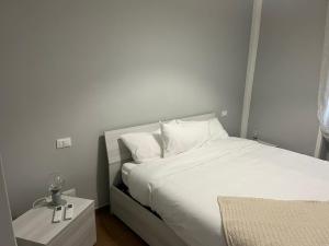 uma cama com lençóis brancos e almofadas num quarto em Podere il Glicine Wellness Charme & Relax em Fresonara