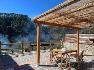 een houten pergola met een tafel en stoelen op een patio bij Podere il Glicine Wellness Charme & Relax in Fresonara