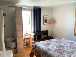 a bedroom with a bed and a desk and a table at Hôtel-Motel Rocher Percé in Perce