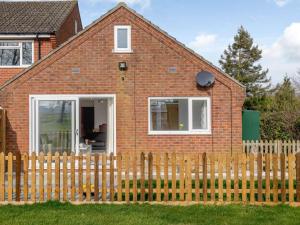 una casa de ladrillo rojo con una valla de madera en 1 Bed in Attleborough 86671, en Caston