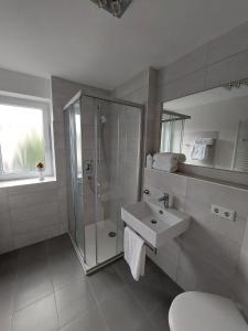a white bathroom with a shower and a sink at Haus am Weinberg in Breitungen