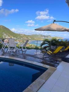 a patio with chairs and an umbrella and a swimming pool at Maison des Brin - Lorient Camaruche in Saint Barthelemy