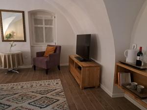 een woonkamer met een televisie en een stoel bij Bem Villa Apartman, Kőszeg in Kőszeg