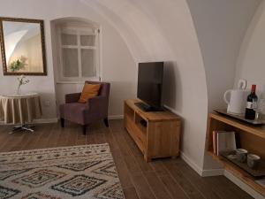 a living room with a television and a chair at Bem Villa Apartman, Kőszeg in Kőszeg
