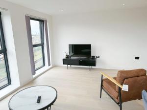 ein Wohnzimmer mit einem TV, einem Sofa und einem Tisch in der Unterkunft Luxury Modern Flat Near Center in London