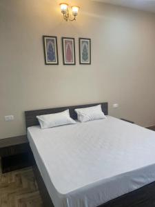 a bedroom with a large white bed with three pictures on the wall at VISTARA COURTYARD in Varanasi
