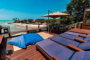 una terraza con camas azules, sombrilla y playa en Laguna Pirangi Beach House, en Parnamirim