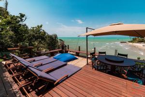 eine Terrasse mit Stühlen, einem Tisch und einem Sonnenschirm in der Unterkunft Laguna Pirangi Beach House in Parnamirim