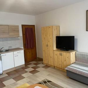 a living room with a kitchen with a flat screen tv at Lenzl's Panzió in Szigetvár