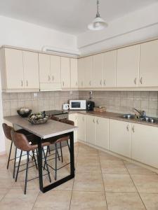 a kitchen with white cabinets and a table with chairs at 'Elia gytheio in Mavrovouni