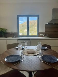 una mesa con platos y vasos en ella en una cocina en Hôtel Résidence CAPENSE, en Centuri