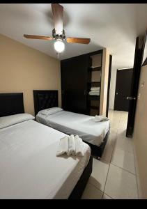 sypialnia z 2 łóżkami i wentylatorem sufitowym w obiekcie Apartahotel a 2 km del Parque del Café, 104A w mieście Montenegro