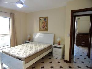 um quarto com uma cama branca e duas mesas de cabeceira em Locação Temporada Cabo Frio RJ. em Cabo Frio