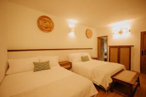 a bedroom with two beds and a clock on the wall at Hotel La Corada in Villa de Leyva