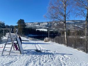 uma pessoa está de pé na neve com um snowboard em Sommerstad em Kongsberg