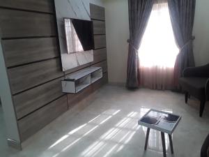 a living room with a television and a table at Franzy Luxury Hotel & Suites in Jos
