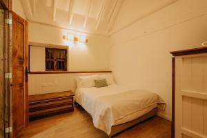 a small bedroom with a bed and a mirror at Hotel La Corada in Villa de Leyva