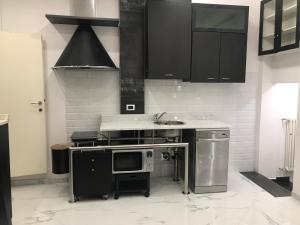 a kitchen with black cabinets and a sink and a microwave at Studio Apartment Santa Caterina in Bologna +7 photos