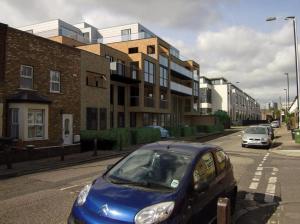 a blue car parked on a city street with buildings at Luxury Modern Flat Near Center in London
