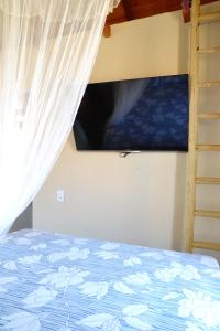 a bedroom with a bed with a curtain and a tv at Chalés Cabocla da Lua in Caraíva