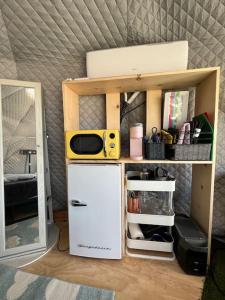 a small kitchen with a microwave on top of a refrigerator at Sunset Dome - Outdoor Shower/Composting Toilet in Valley Center