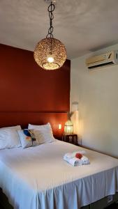 Un dormitorio con una gran cama blanca y una lámpara de araña. en Ayo Bistrô Pousada en Marau