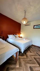 Habitación de hotel con 2 camas y lámpara de araña. en Ayo Bistrô Pousada, en Maraú