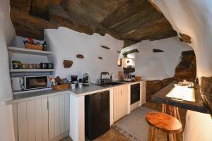 a kitchen with white cabinets and a stone wall at M&K kelè Zannel seaside serenity in Kardhianí
