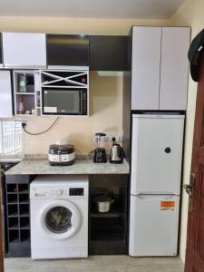 uma cozinha com um frigorífico branco e uma máquina de lavar roupa em AJALA Lodge em Badagry