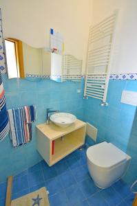 een blauw betegelde badkamer met een toilet en een wastafel bij CASA MONDRIAN in Tiggiano