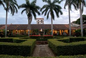 a building with a clock tower and palm trees at Hotel El Convento Leon Nicaragua in León