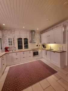 uma grande cozinha com armários brancos e um tapete vermelho em Beautiful townhouse, piece of luxury em Pori
