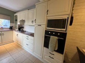 cocina con armarios blancos y microondas en For contractors nr Worthing station large 4 bed 2bath house sleeps 10 by Eagle Owl Property, en Worthing