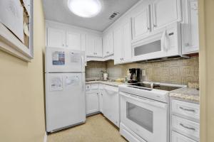 a white kitchen with white appliances and white cabinets at The Shell House at Horizon South in Panama City Beach