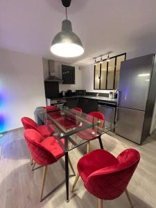 een keuken met een glazen tafel en rode stoelen bij Hypercentre * Pop * Calme - Le Grand Rétro in Pontarlier