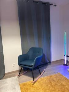 een blauwe stoel in een kamer met een tapijt bij Hypercentre * Pop * Calme - Le Grand Rétro in Pontarlier