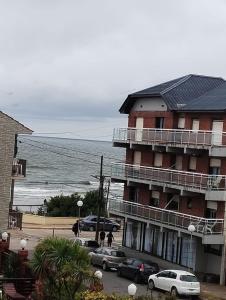 un gran edificio con coches estacionados frente al océano en Almirante Brown 49, en Mar de Ajó