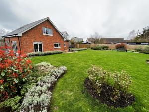 a brick house with a yard with flowers at Laurel Cottage in Sandown