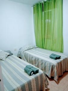 - 2 lits dans une chambre avec des rideaux verts dans l'établissement Playa Beach Malaga 3habts dobles, cocina familiar, apartamento completo, à Cala del Moral