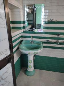 uma casa de banho com um lavatório verde e um espelho em Mahadev Retreat em Faizābād