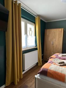 Schlafzimmer mit einem Bett und einem Fenster mit gelben Vorhängen in der Unterkunft Pension Victoria in Halberstadt
