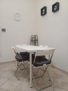 una mesa blanca con dos sillas y un reloj en la pared en Repubblica 14, en Iglesias
